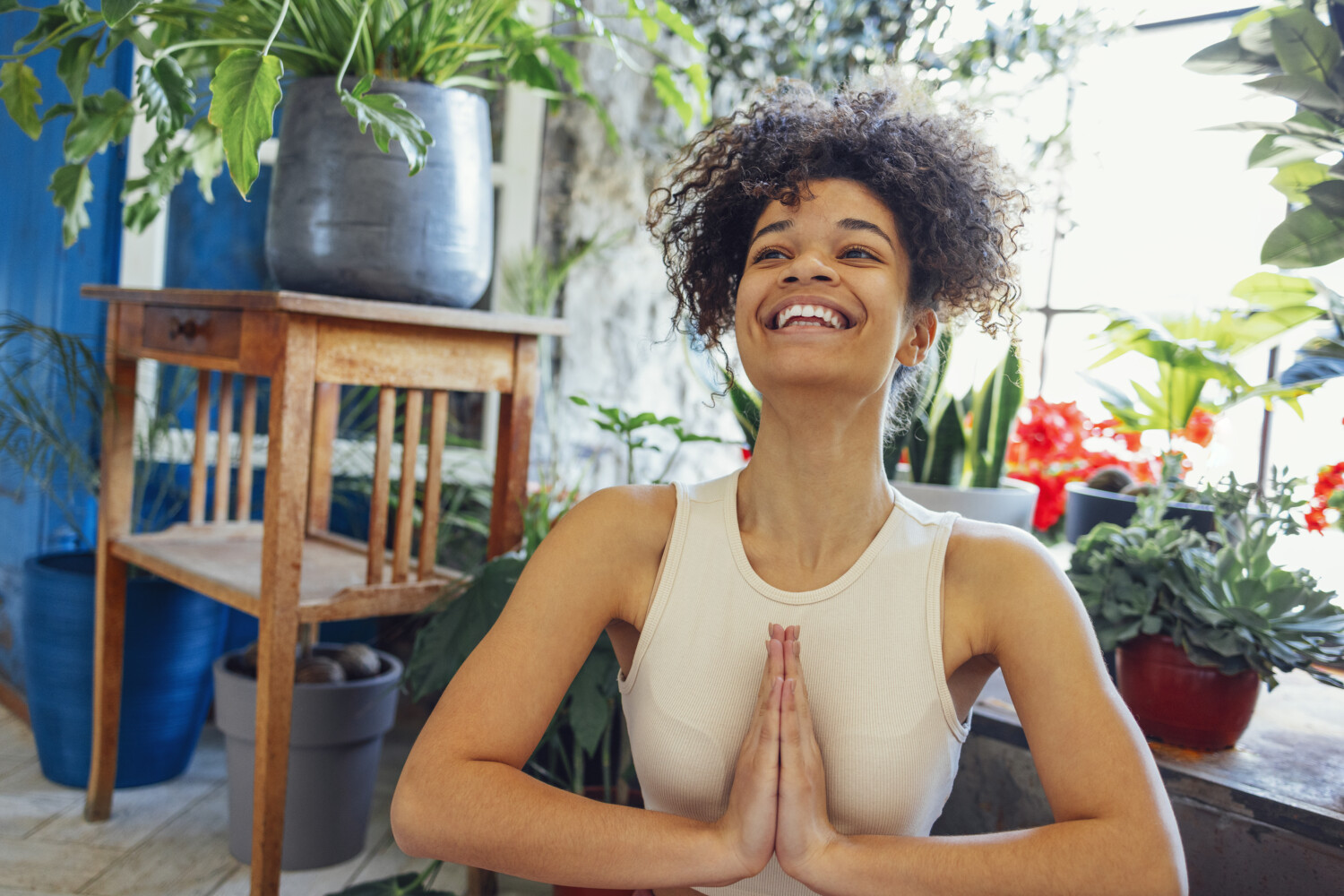 Young adult happy fit slim healthy African American ethnic woman wearing sportswear sitting in yoga pose at home in living room, doing fitness morning workout exercises training.